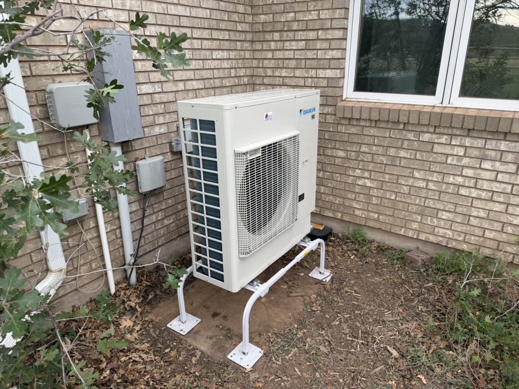 Daikin heat pump on a stand against brick — Grants HVAC install